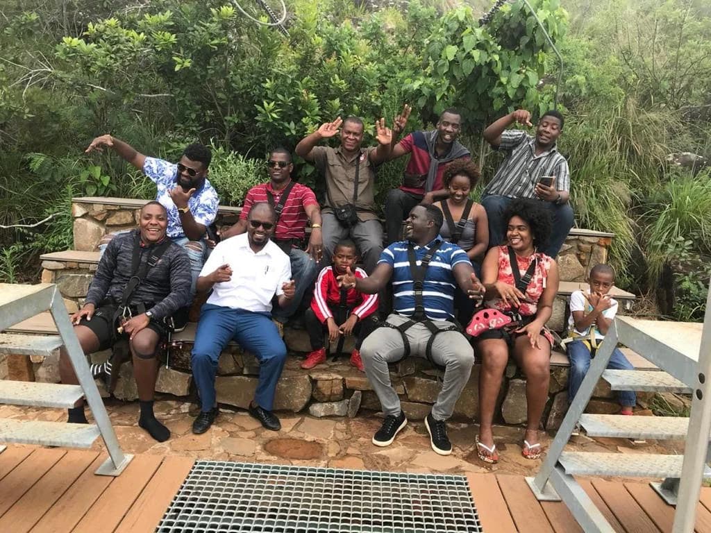 Grupo em sessão de team building, sorridente durante uma atividade de arborismo ao ar livre